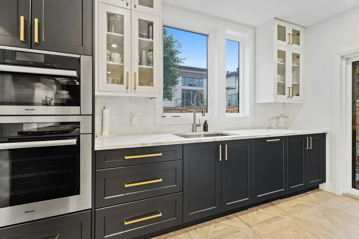 Custom kitchen with dark gray shaker cabinets, brass hardware, glass-front uppers and marble countertops by Makiry Group in Sarasota, FL