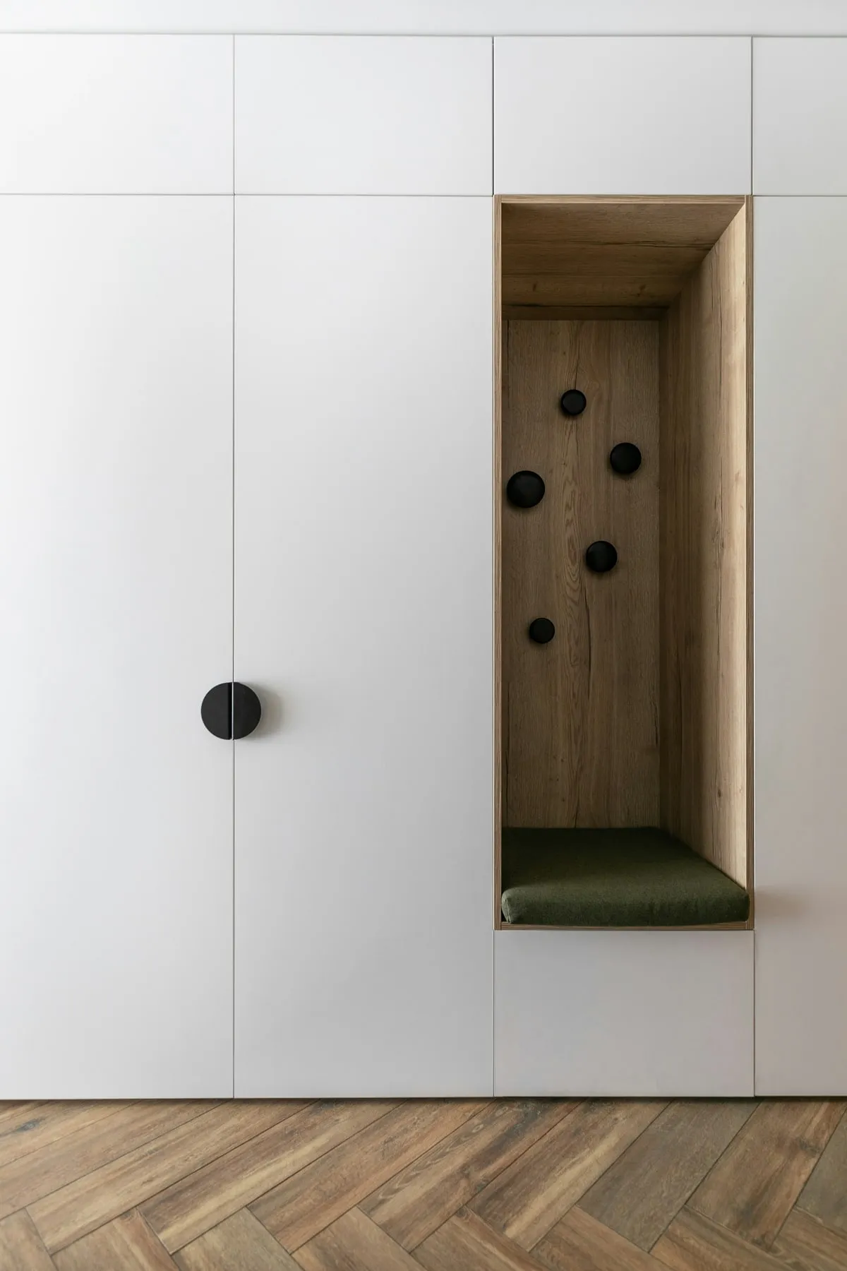 Custom white walk-in closet with a warm oak interior, black hardware and a cushioned bench, built by Makiry Group in Sarasota, FL