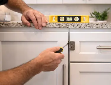 Technician using a level to align cabinets during a repair in Sarasota, FL